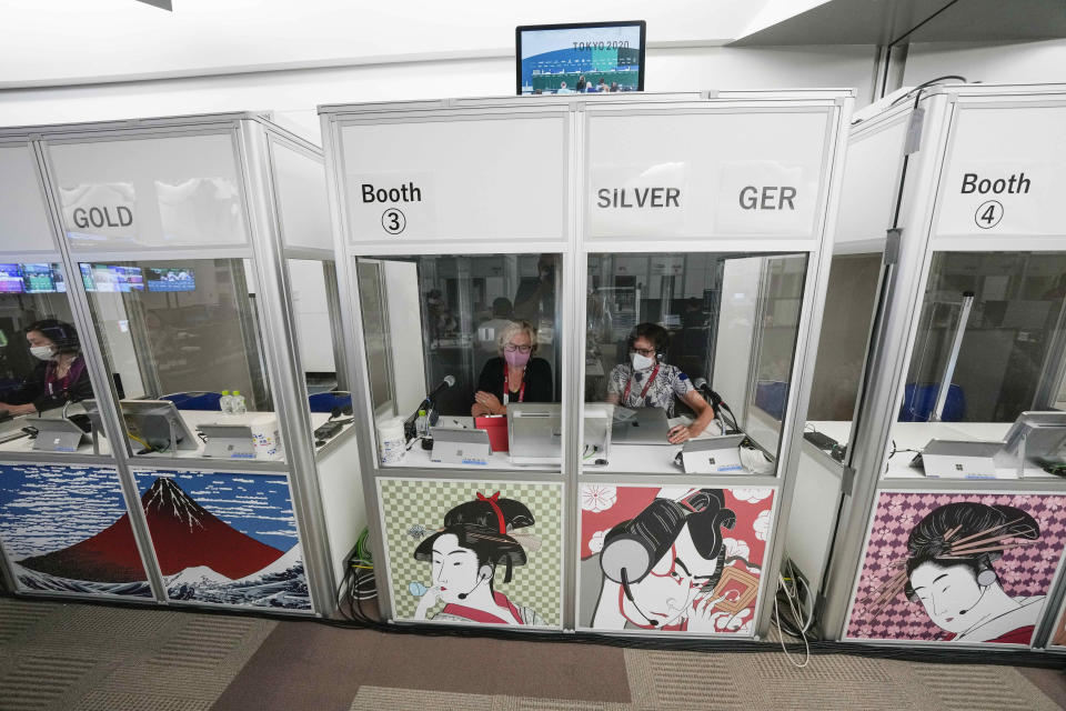 Interpreters work at the main press center during the 2020 Summer Olympics, Friday, July 30, 2021, in Tokyo, Japan. Unlike previous Olympics, all the interpretation is being done remotely with most interpreters working in booths at the main center. Their simultaneous translation can be accessed at all Olympic venues on an app. This eliminates interpreters getting tied up in traffic heading to an venue. (AP Photo/Luca Bruno)