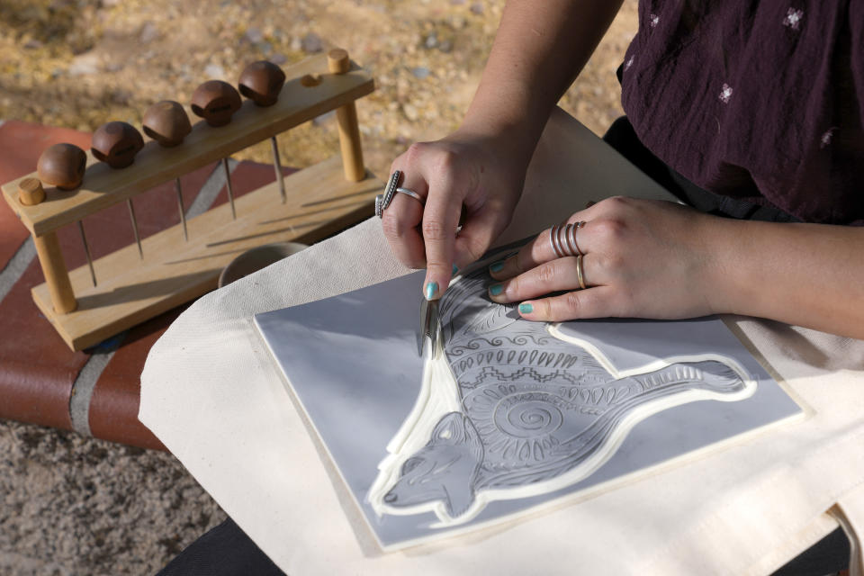 Olivia Yuen, 29, a middle school art teacher and well-known artist in Phoenix, who has a Chinese father and a Mexican mother, works on a linocut piece Tuesday, May 21, 2024, in Laveen, Ariz. (AP Photo/Ross D. Franklin)