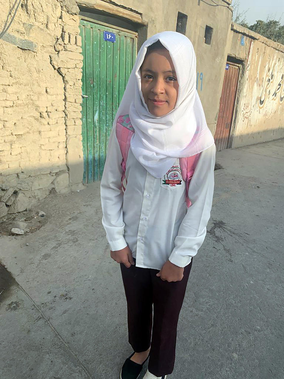 An Afghan school girl poses for a photograph on the road after the U.S. withdrawal in Kabul, Afghanistan, Tuesday, Aug. 31, 2021. The Taliban were in full control of Kabul's international airport on Tuesday, after the last U.S. plane left its runway, marking the end of America's longest war. (AP Photo/Kathy Gannon)