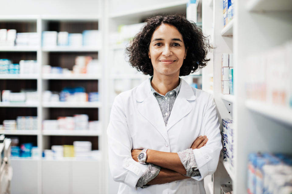 A portrait of a pharmacist standing next some medical supplies in her pharmacy store in the city.