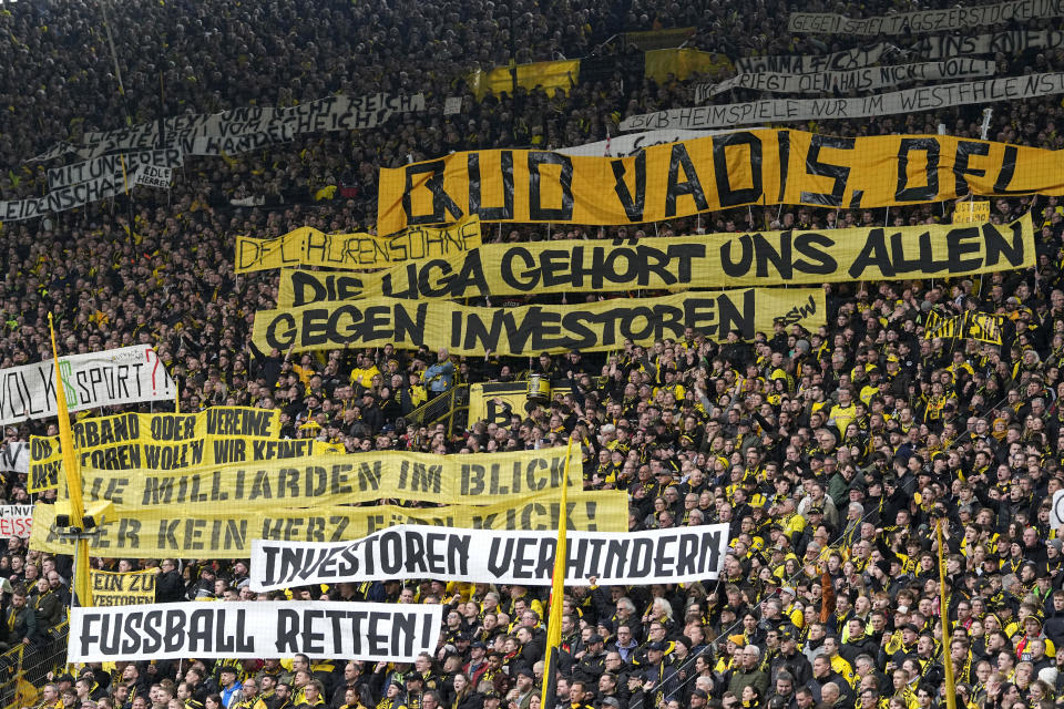 FILE - Fans hold up banners protesting against investors in German soccer during the German Bundesliga soccer match between Borussia Dortmund and Union Berlin in Dortmund, Germany, on, April 8, 2023. From Brazil to Spain to Australia and beyond, the soccer landscape is changing quickly with a surge of investment firms injecting billions into clubs and leagues around the world. After a wave of wealthy states, billionaires and oligarchs getting into the sport, now it’s time for investment groups to start making a push to leave their footprints and earn a profit. (AP Photo/Martin Meissner, File)