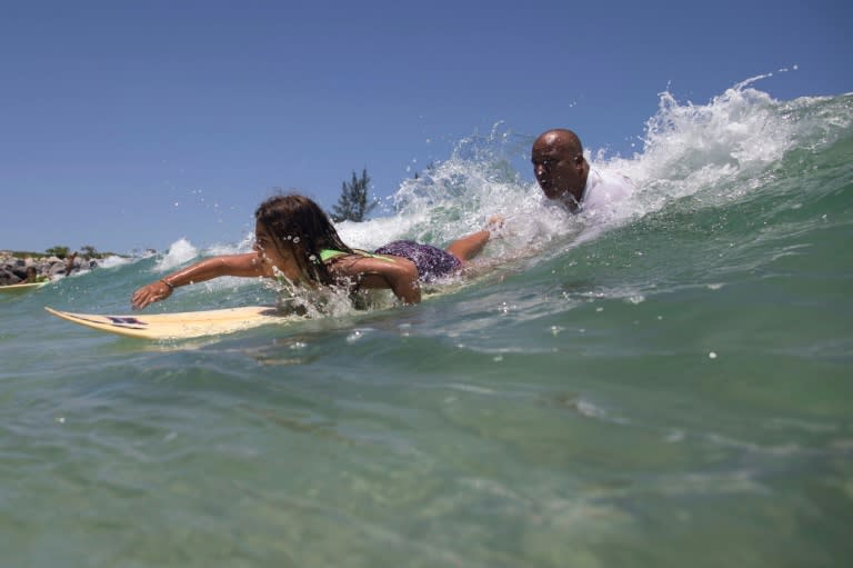 Luiz Augusto de Matos (R), 50, one of the teachers at Saquarema Surf School, helps his pupil Luana Felix, 11, to take a wave