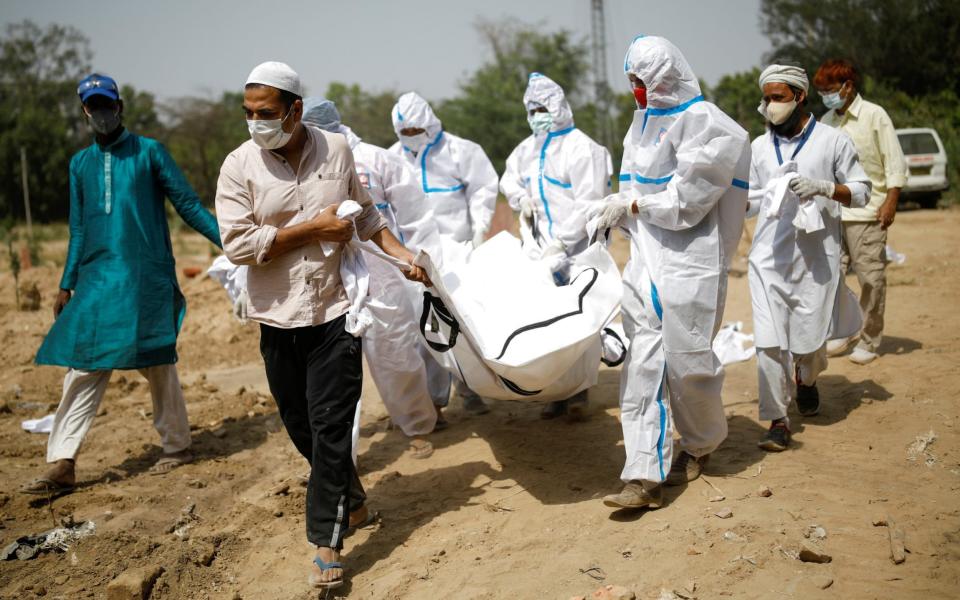 Relatives carry the body of a man who died from Covid-19, during his funeral at a graveyard in New Delhi - Adnan Abidi/Reuters