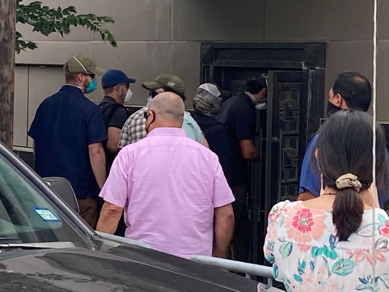 A group of people use power tools to try to pry open a rear door of the Chinese consulate in Housto