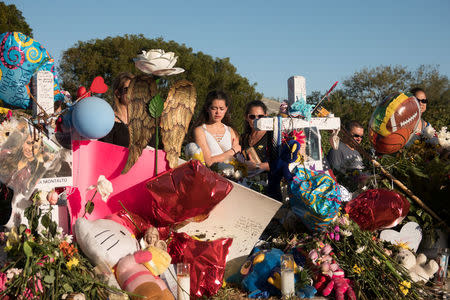 Well-wishers place mementos the day students and parents arrive for voluntary campus orientation at the Marjory Stoneman Douglas High School, for the coming Wednesday's reopening, following last week's mass shooting in Parkland, Florida, February 25, 2018. REUTERS/Angel Valentin