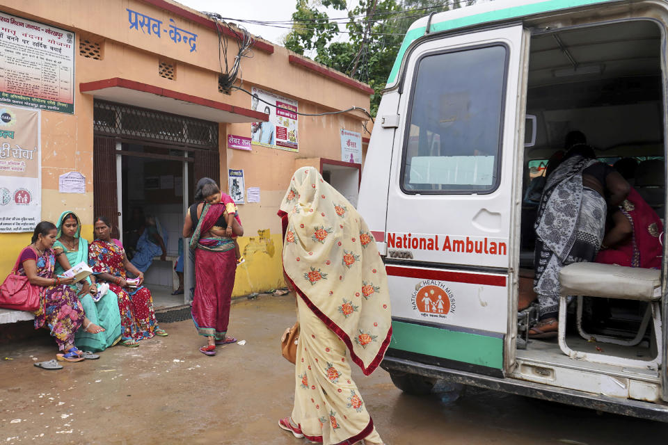 In this Sept. 13, 2019, photo, a woman carries a child suspected of having encephalitis into the Primary Health Center in Khorabar, in the northern Indian state of Uttar Pradesh. Cases of encephalitis, or inflammation of the brain, in Uttar Pradesh, India's most populated state with millions of rural poor, have dropped sharply. Doctors and state government officials credit a new network of rural clinics and a massive immunization and cleanliness drive in seven districts with the highest caseloads of the disease that's often deadly. An independent physician says there's no way to independently verify the government's claims, but that a decline is visible. (AP Photo/Usman Ahmad)