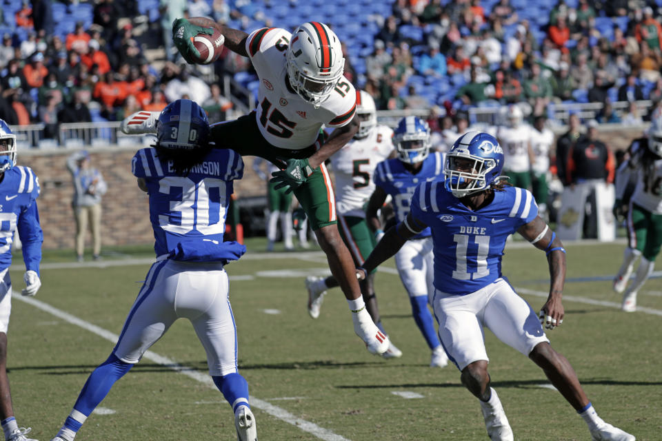 Miami wide receiver Jacolby George (15) gets upended as he tries to hurdle over Duke safeties Brandon Johnson (30) and Isaiah Fisher-Smith (11) on a punt return during the first half of an NCAA college football game Saturday, Nov. 27, 2021, in Durham, N.C. (AP Photo/Chris Seward)