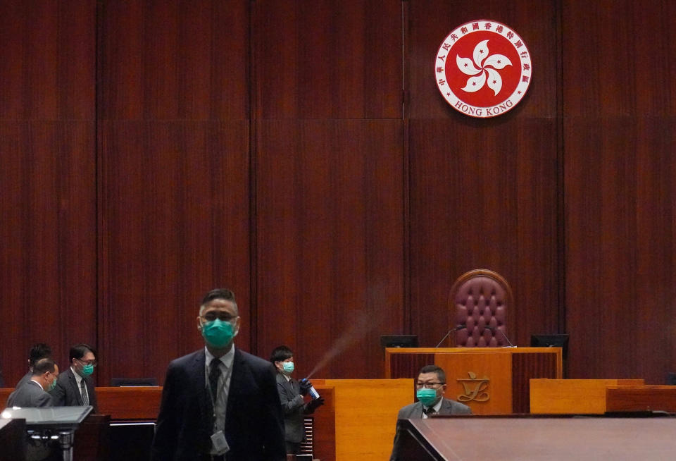 Security from the Legislative Council guard and disinfect after a pro-democracy lawmaker hurled an object during the second day of debate on a bill that would criminalize insulting or abusing the Chinese anthem in Hong Kong, Thursday, May 28, 2020. The lawmaker ejected later had spilled a substance on the floor that had to be cleaned up by firefighters wearing protective gear.(AP Photo/Vincent Yu)