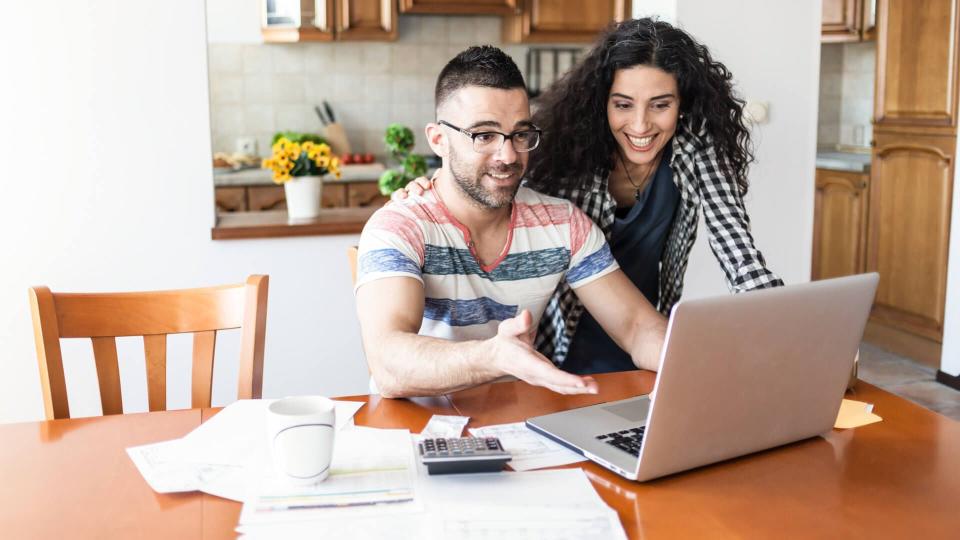 Couple working at home, using laptop.