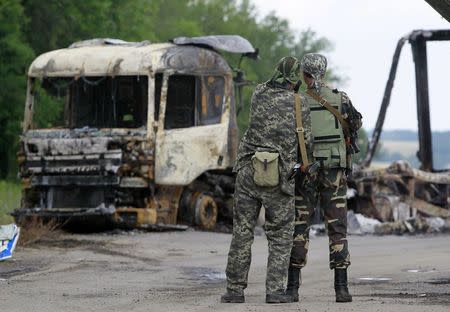 Pro-Russian separatists stand guard at a checkpoint near a burnt truck outside Luhansk, June 18, 2014. REUTERS/Shamil Zhumatov
