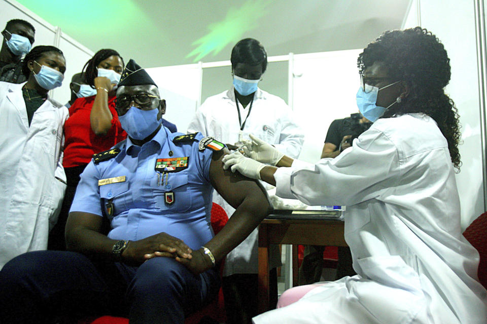 FILE - In this March 1, 2021, file photo, Youssouf Kouyate, National Police General Director, receives a shot of the AstraZeneca vaccine in Abidjan, Ivory Coast. The COVAX global initiative is providing vaccines to poorer countries lacking the clout to negotiate for them on their own, but on March 25, COVAX announced a major setback in its vaccine rollout because a surge in infections in India had caused the Serum Institute of India to cater to domestic demand, resulting in a delay in global shipments of up to 90 million doses. (AP Photo/Diomande Ble Blonde, File)