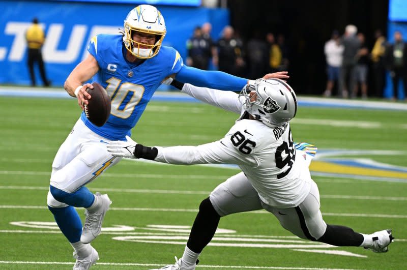 Los Angeles Chargers quarterback Justin Herbert (L) runs by Las Vegas Raiders defender Isaac Rochell in first quarter action Sunday at SoFi Stadium in Inglewood, Calif. Photo by Jon SooHoo/UPI