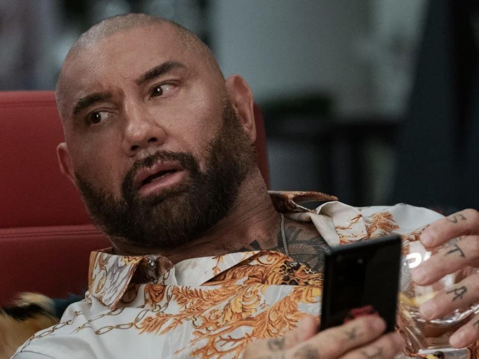 Dave Bautista as Duke Cody holding his phone.