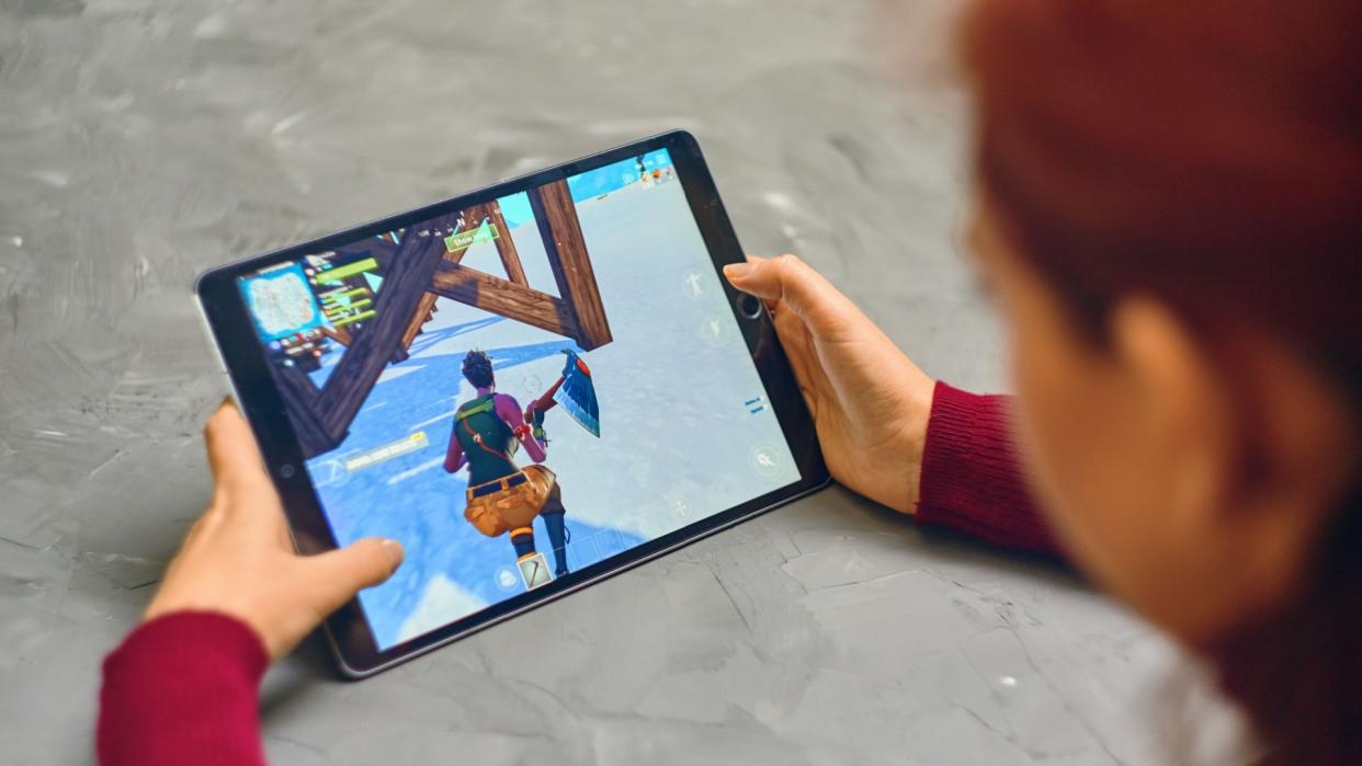  Woman playing fortnite game of epic games company on Apple ios tablet. 