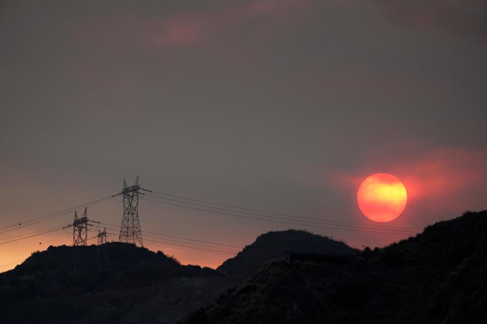 The sun sets through smoke created by the Ranch Fire, Thursday, Aug. 13, 2020, in Azusa, Calif. Heat wave conditions were making difficult work for fire crews battling brush fires and wildfires across Southern California.