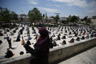 FILE - In this Friday, May 29, 2020, file photo, a woman takes pictures as worshippers wearing face masks and observing social distancing guidelines to protect against coronavirus, attend Friday prayers, outside Fatih mosque, in Istanbul. When Turkey changed the way it reports daily COVID-19 infections, it confirmed what medical groups and opposition parties have long suspected — that the country is faced with an alarming surge of cases that is fast exhausting the Turkish health system. The official daily COVID-19 deaths have also steadily risen to record numbers in a reversal of fortune for the country that had been praised for managing to keep fatalities low. With the new data, the country jumped from being one of the least-affected countries in Europe to one of the worst-hit. (AP Photo/Emrah Gurel, File)