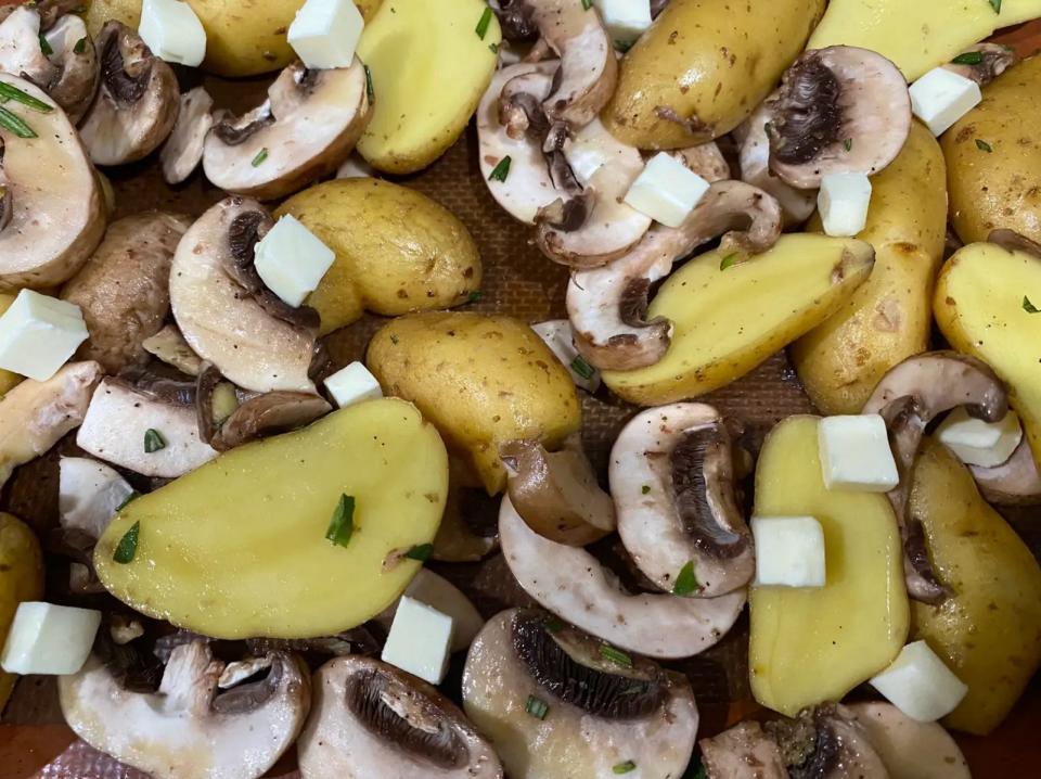 mushrooms, potatoes, butter, and seasoning spread out on a sheet pan