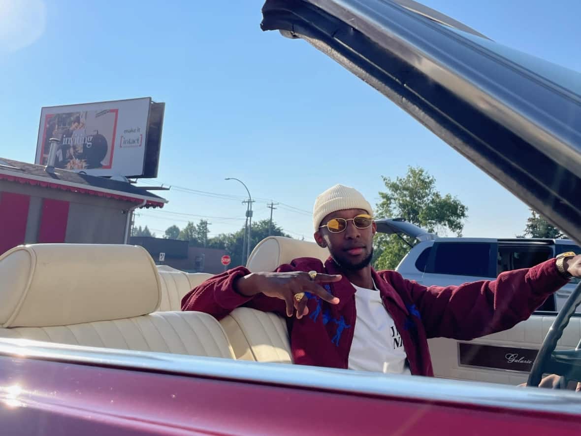 Ntwali Kayijaho behind the wheel of Adam Kaminski's red 1969 Ford Galaxie 500 convertible during the video shoot for Kayijaho's Message to the Youth.    (Saint Diego - image credit)