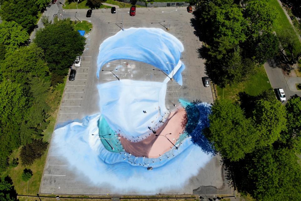 Artist Jorge Rodriguez-Gerada works on a 20,000 square foot mural of a health care worker in a parking lot in Flushing Meadows Corona Park in the Queens borough of New York, Wednesday, May 27, 2020. The mural is to honor those who lost their lives during the coronavirus pandemic, especially minority health care workers. The portrait was inspired by Dr. Ydelfonso Decoo, an immigrant doctor who died from coronavirus complications while serving hard-hit communities of color.