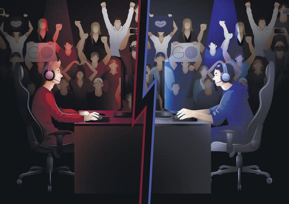 Two video gamers, one dressed in red and one in blue, sitting at desk facing each other with audiences for each side shown cheering in the background.