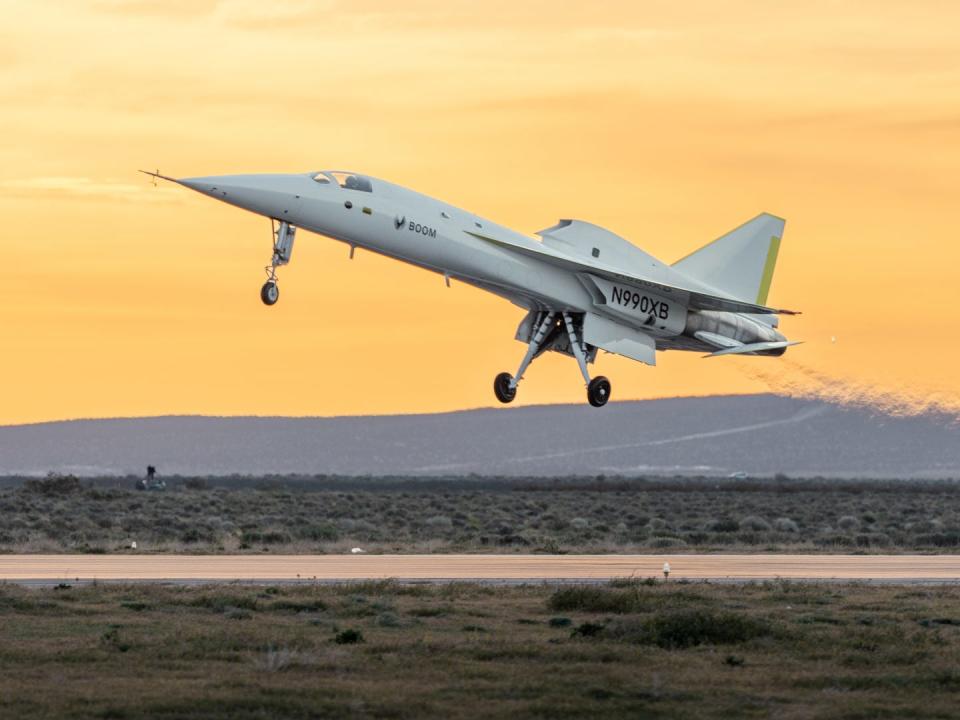 The XB-1 taking off over the desert with mountains in background.