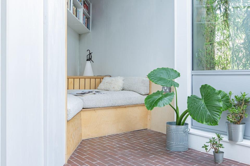 A couch, plants, and a bookshelf in a triangle-shaped house.