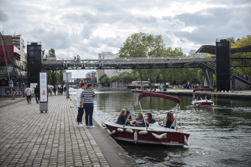 People enjoy a ride with a small boat on La Villette Canal, in Paris, France, Saturday, June 5, 2021. (AP Photo/Lewis Joly)