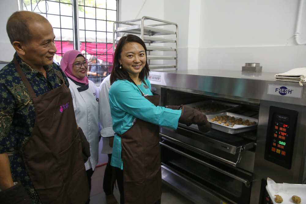 Hannah Yeoh puts a tray of cookies into the oven during the launch of the Women of Will's Community Kitchen in Kuala Lumpur May 25, 2019. ― Pictures by Yusof Mat Isa