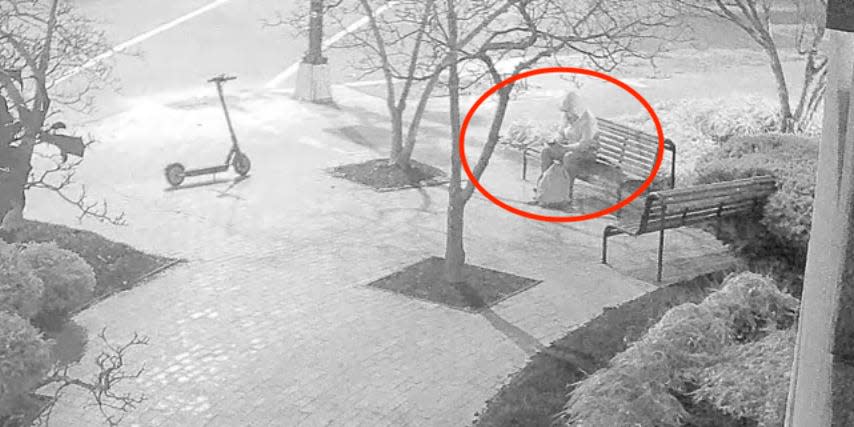 Security footage of a person sitting on park bench.