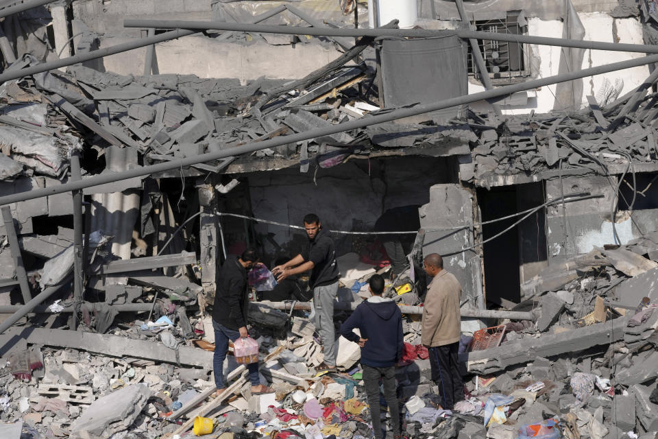 Palestinians salvage belongings from the destroyed Al-Gatshan family building after an Israeli strike in Nusseirat refugee camp, central Gaza Strip, Monday, Dec. 18, 2023. (AP Photo/Adel Hana)