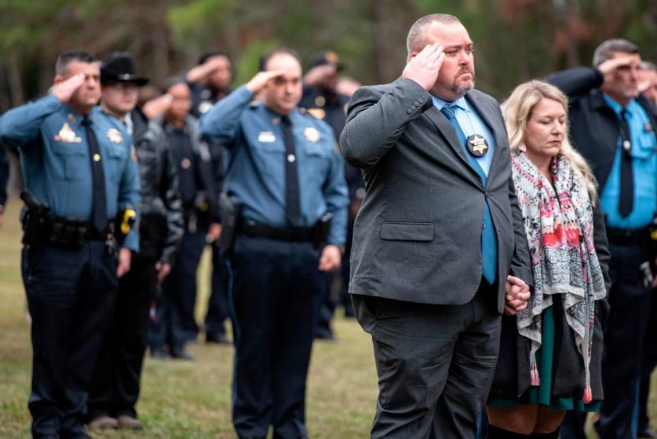 Law enforcement officers salute during the funeral of Bay St. Louis police officers Sgt. Steven Robin and Branden Estorffe at Gardens of Memory cemetery in Bay St. Louis on Wednesday, Dec. 21, 2022. Robin and Estorffe were killed responding to a call at a Motel 6 on Dec. 14.