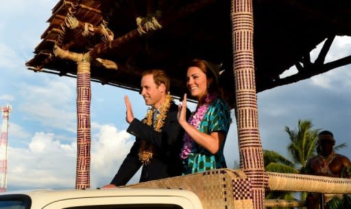 Britain's Prince William and his wife Catherine, the Duchess of Cambridge, wave to locals as they leave the airport aboard a truck decorated as a canoe, in Honiara on September 16. Britain's royal family were struggling Sunday to prevent the spread of topless photographs of Catherine, after the threat of legal action failed to intimidate Irish and Italian titles