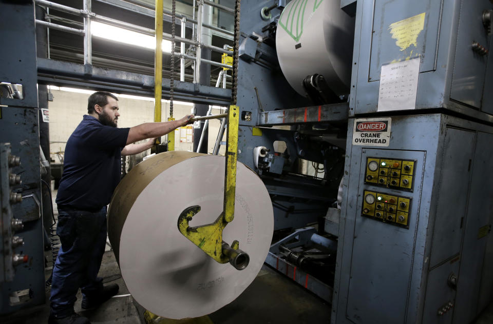 In this Thursday, April 11, 2019 photo pressman Adam Doucette, of Pittsfield, Mass., prepares a roll of paper for printing presses at The Berkshire Eagle newspaper, in Pittsfield. The paper now features a new 12-page lifestyle section for Sunday editions, a reconstituted editorial board, a new monthly magazine, and the newspaper print edition is wider. That level of expansion is stunning in an era where U.S. newspaper newsroom employment has shrunk by nearly half over the past 15 years. (AP Photo/Steven Senne)