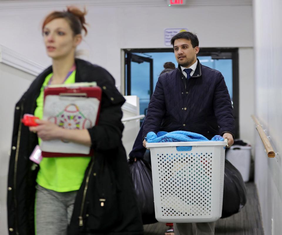 Mayor Shammas Malik, right, carries in laundry for Akron residents during the Tumble Together Thursday event at Super Clean Laundromat on Thursday.