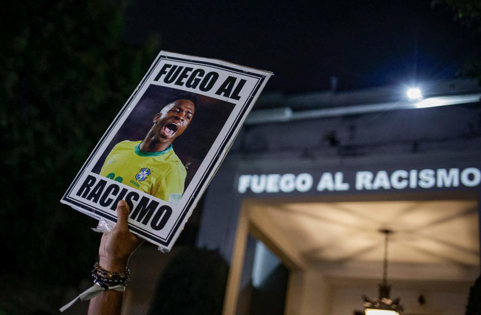 A protester holds up a photo of Brazilian soccer star Vinicius Jr and a message that reads in Portuguese; "Fight racism" during a protest outside the Spanish Consulate in Sao Paulo, Brazil, Tuesday, May 23, 2023.