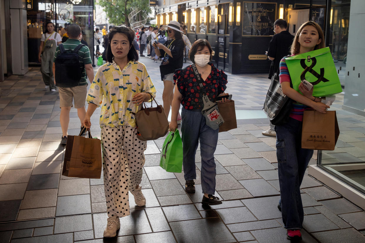 People carry shopping bags in a shopping district in Beijing, China, July 14, 2023. REUTERS/Thomas Peter