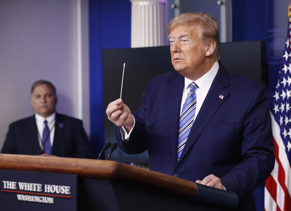 President Donald Trump holds a swab that could be used in coronavirus testing as he speaks during a coronavirus task force briefing at the White House.