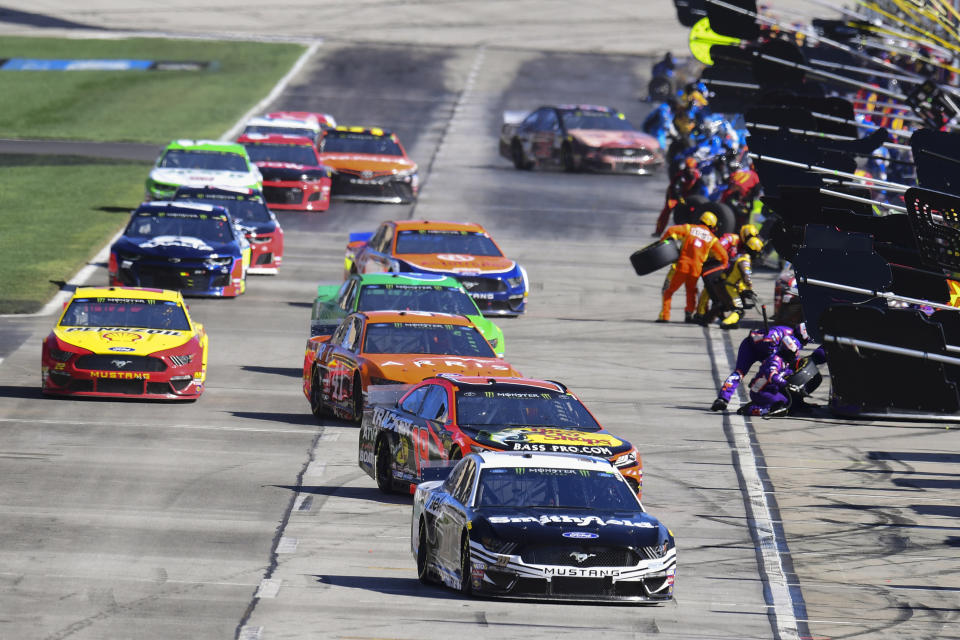 Aric Almirola (10) is followed by Martin Truex Jr. (19) as they and others pit during a NASCAR Monster Energy NASCAR Cup Series auto race at Atlanta Motor Speedway, Sunday, Feb. 24, 2019, in Hampton, Ga. (AP Photo/Scott Cunningham)