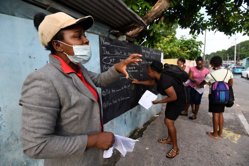 Educator Mckoy Phipps teaches a lesson next to a blackboard painted on a wall during the coronavirus disease (COVID-19) outbreak in Kingston