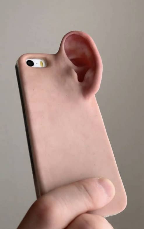 Phone case shaped like a human ear held in a person's hand