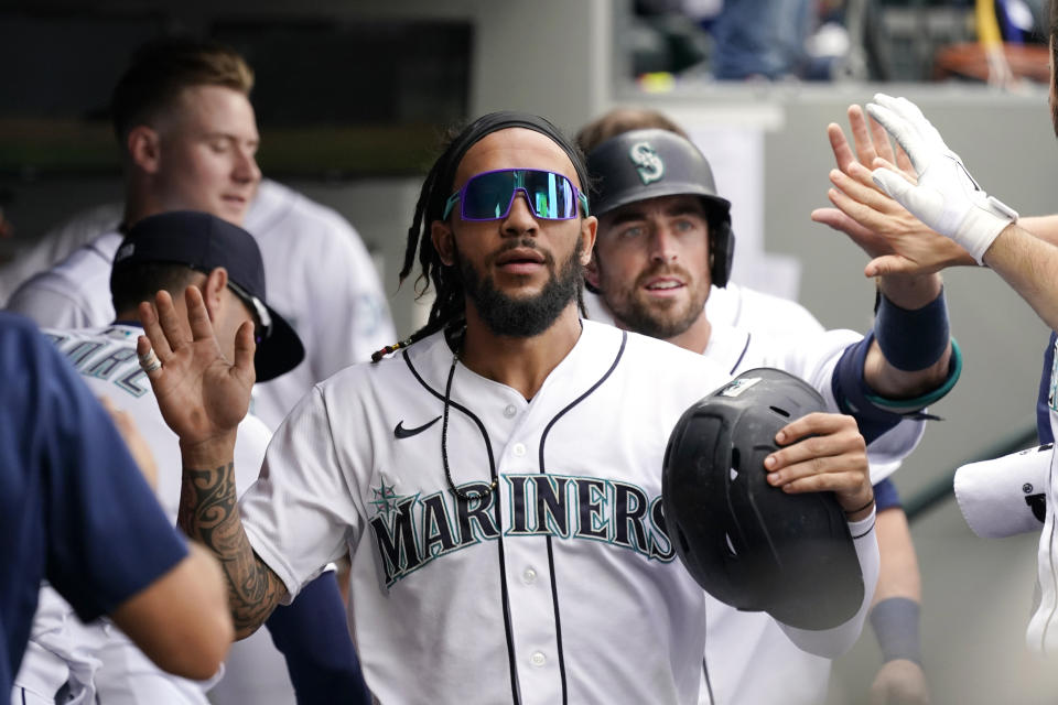 Seattle Mariners' J.P. Crawford is followed by Tom Murphy as teammates congratulate them after both scored against the Boston Red Sox in the third inning of a baseball game Wednesday, Sept. 15, 2021, in Seattle. (AP Photo/Elaine Thompson)