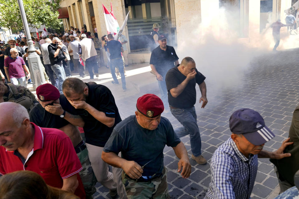 Retired members of the army run from tear gas fired by riot police near the parliament as the legislature was in session discussing the 2022 budget, during a protest in downtown Beirut, Lebanon, Monday, Sept. 26, 2022. The protesters demanded an increase in their monthly retirement pay, decimated during the economic meltdown. (AP Photo/Bilal Hussein)