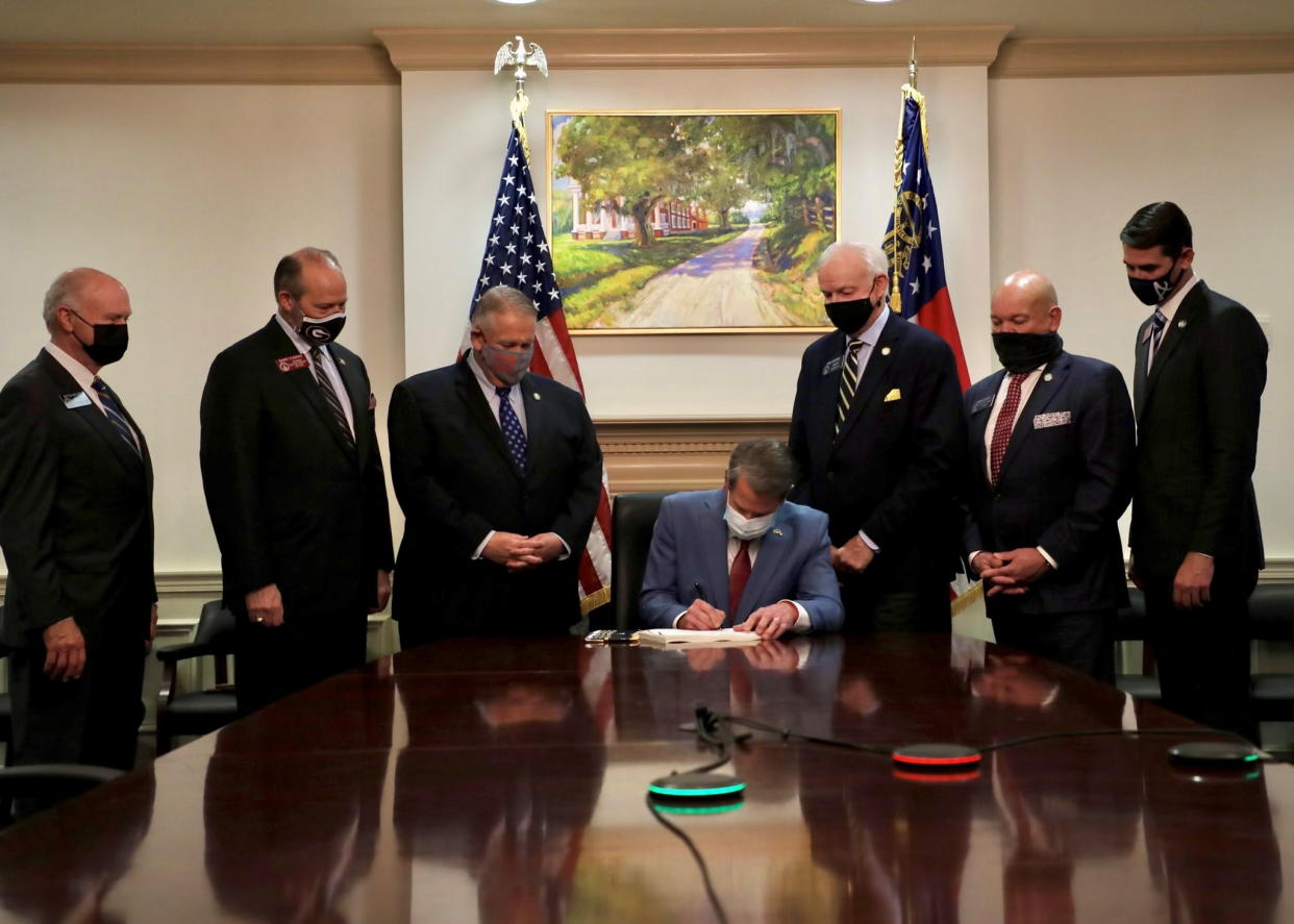 Republican Governor Brian Kemp signs the law S.B. 202, a restrictive voting law that activists have said aimed to curtail the influence of Black voters who were instrumental in state elections that helped Democrats win the White House and narrow control of the U.S. Senate, in this handout photo posted to Kemp's Twitter feed on March 25, 2021. (Governor Brian Kemp's Twitter feed/Handout via Reuters)