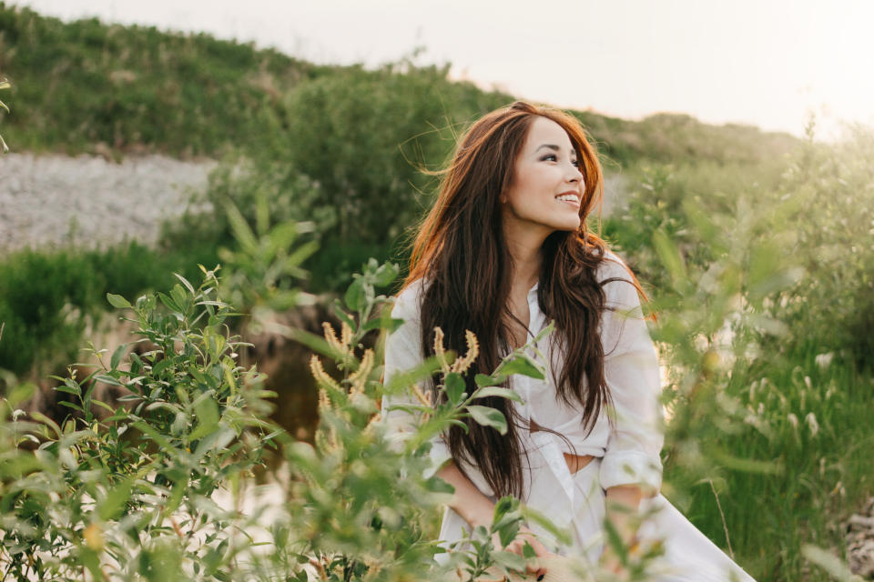 Beautiful carefree long hair asian girl in the white clothes on river side in grass at sunset. Sensitivity to nature conceptÀ€