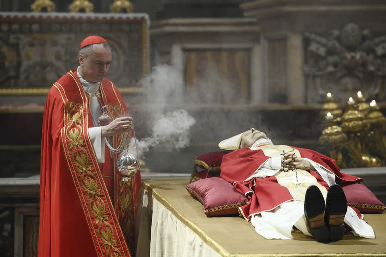 En esta imagen publicada el lunes 2 de enero de 2023 por el servicio de noticias Vatican Media, el cardenal Mauro Gambetti inciensa el cuerpo del difunto papa emérito Benedicto XVI en el interior de la basílica de San Pedro en el Vaticano. (Vatican Media vía AP)