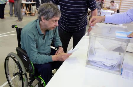 A man in a wheelchair casts his vote during the regional parliamentary elections at a polling station in Vigo, northern Spain, September 25, 2016. REUTERS/Miguel Vidal