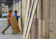 Two workers board up a store front, Wednesday, Oct. 28, 2020, in Philadelphia. Demonstrators protested the death of Walter Wallace Jr., who was fatally shot by police Monday after authorities say he ignored orders to drop a knife. Some businesses were cleaning up damage after video showed people streaming into stores and stealing goods on the opposite side of the city from where Wallace was shot. (AP Photo/Michael Perez)