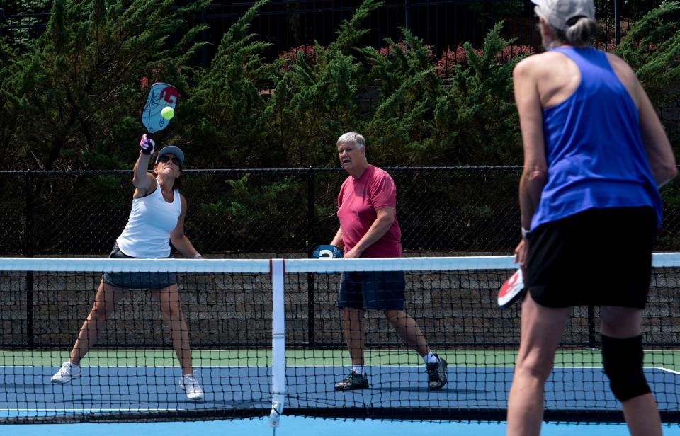 Carol Moriarty, left, goes for an overhead slam with partner John Sabo, center, against pickleball opponents Trish Hollenga and Mark Grasela, not pictured, at Del Webb Sports Complex in Mt. Juliet, Tenn., Wednesday, June 12, 2024. Del Webb at Lake Providence will hold a pickleball party to benefit the Alzheimer Association’s Tennessee chapter on June 20.