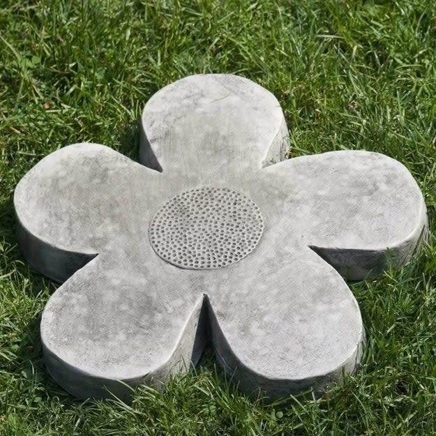 Concrete flower-shaped stepping stone on green grass