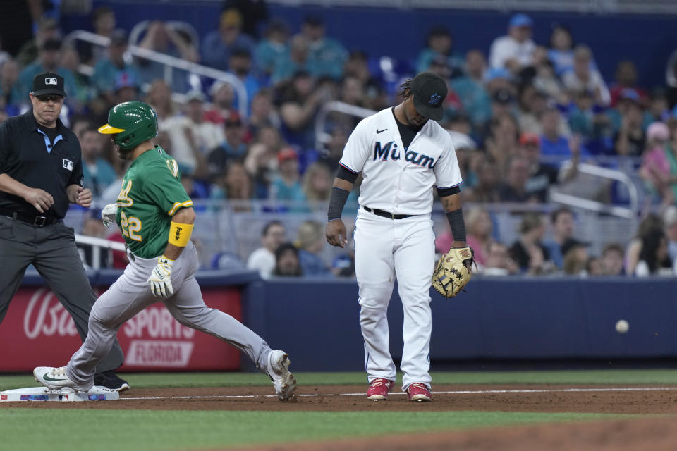 Miami Marlins third baseman Jean Segura, right, reacts after missing a catch on a throwing error by starting pitcher Sandy Alcantara (not shown) as Oakland Athletics' Ramon Laureano (22) heads for home to score during the third inning of a baseball game, Sunday, June 4, 2023, in Miami. (AP Photo/Wilfredo Lee)